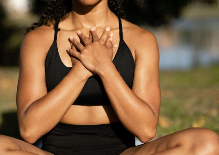 Woman practicing mindfulness outdoors with hands on heart to support mental fitness and emotional well-being.